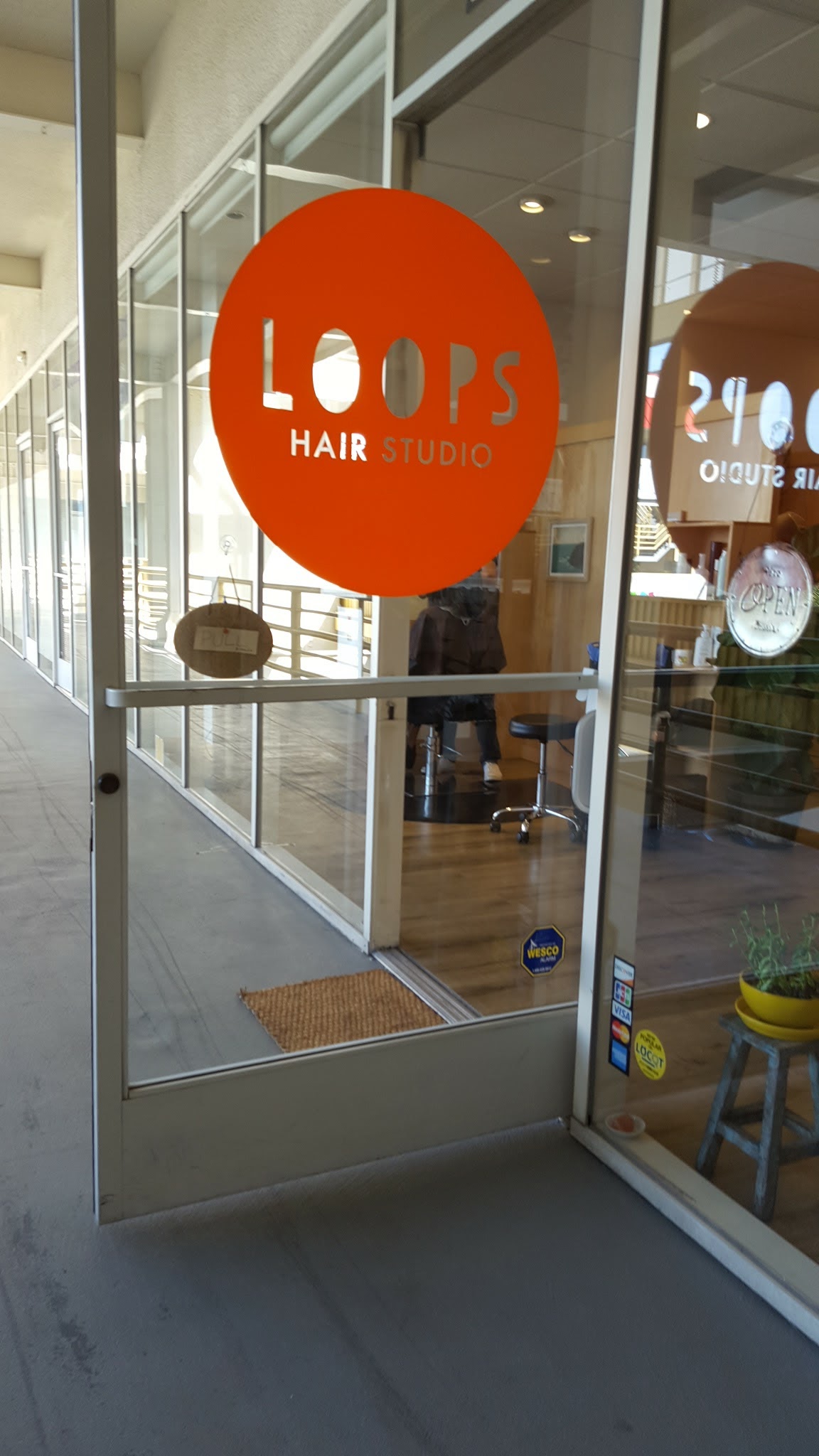 The orange Loops Hair Studio sign on the entrance door at Sawtelle Plaza